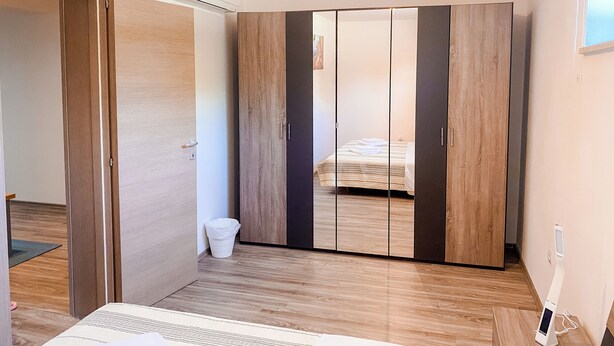 Un dormitorio con un armario, una cama y un pequeño cubo de basura.