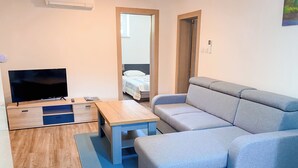 Una sala de estar moderna con un sofá, una mesa de centro, un televisor y una cama.