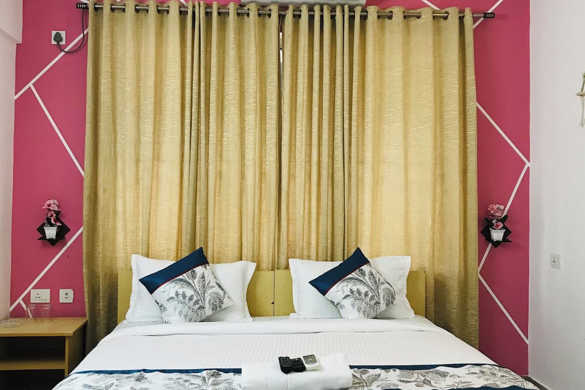 A hotel room with a bed, curtains, a ceiling fan, and an air conditioning unit.