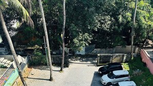 A parking area with several cars, a paved walkway, and surrounding greenery. - HOTEL MELVET RESIDENCY (Kanayannur)