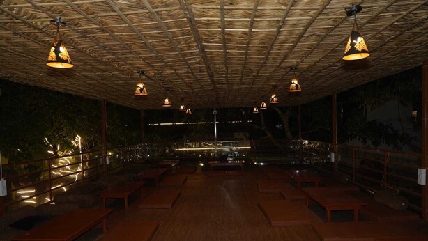 An indoor seating area with wooden benches and hanging lamps. - Tree Aura Retreat (Rishikesh)