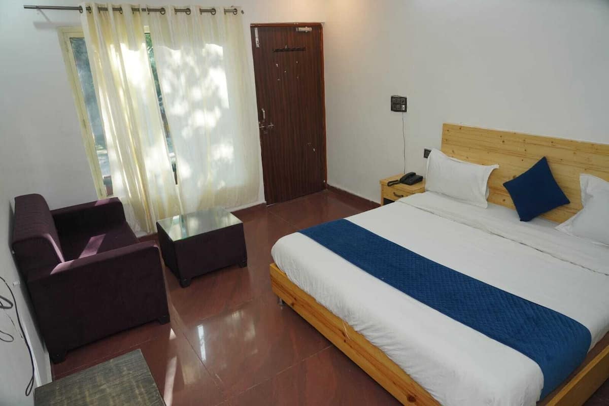 Une chambre d’hôtel avec un lit, une petite table, une chaise et une porte en bois.
