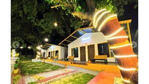 A building with a sloped roof, multiple windows, and a paved entrance area. - Tree Aura Retreat (Rishikesh)