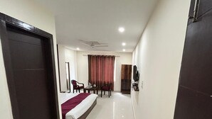 A hotel room with a bed, a desk, a chair, a television, and a fireplace. - Hotel Excotia Haridwar (Haridwar)