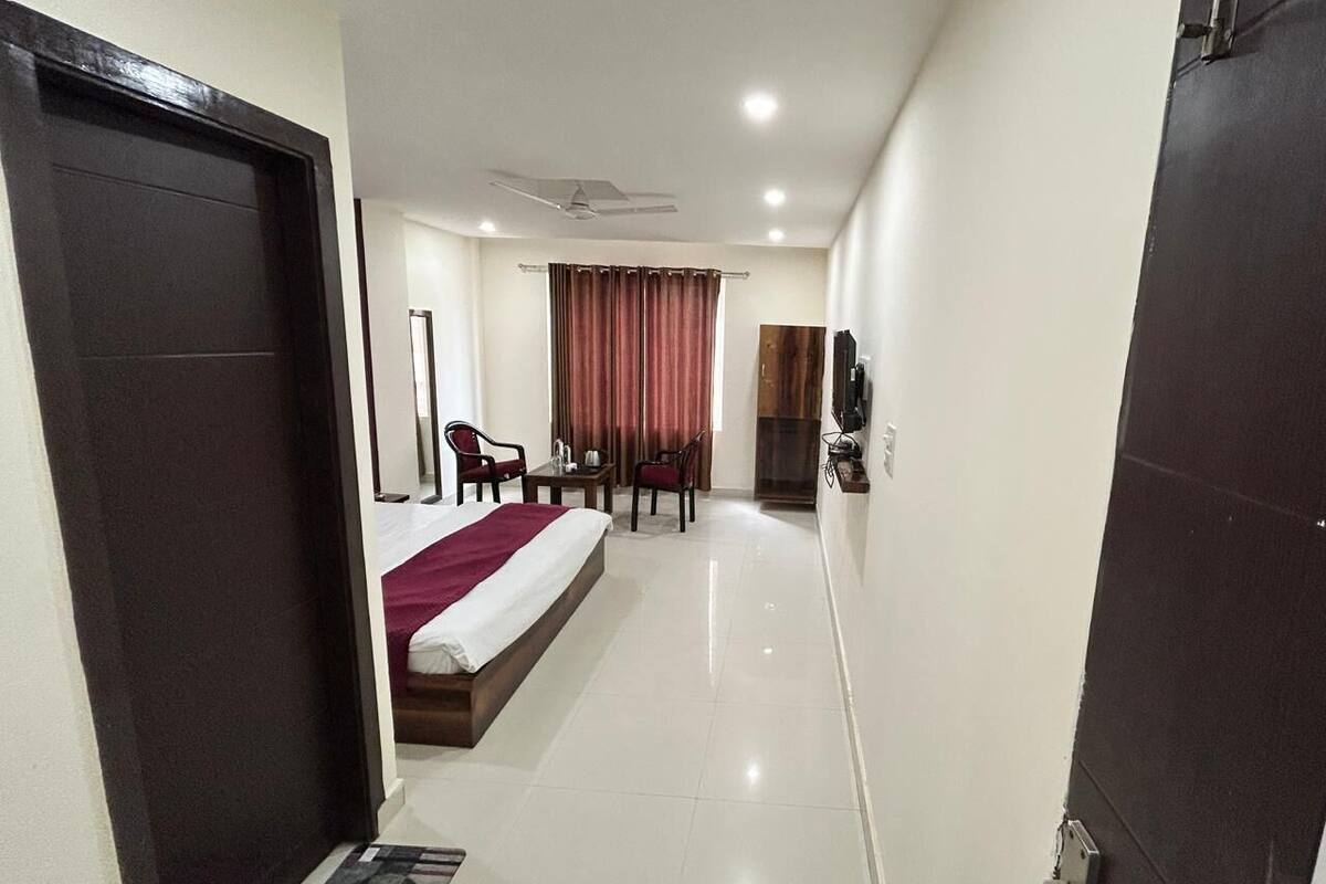 A hotel room with a bed, a desk, a chair, a television, and a fireplace.