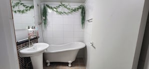 Une salle de bain avec une baignoire sur pieds, un lavabo et un miroir.