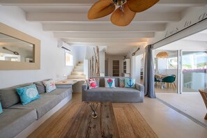 A modern living room with a sofa, coffee table, and a dining area with chairs. - Villa Lantana with private pool - My Rental Homes (Santa Eulària Des Riu)