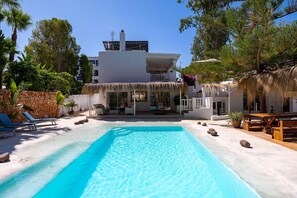 A pool with a clear blue water surface, a white building with a balcony, and surrounding greenery. - Villa Lantana with private pool - My Rental Homes (Santa Eulària Des Riu)