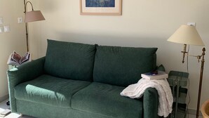 A green sofa with a white throw blanket, a framed abstract painting, and two floor lamps. - Chuchotis, apartment for 4 with balcony and parking space (LE Crotoy)