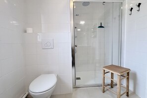 A bathroom with a toilet, a glass shower enclosure, and a wooden stool. - Chuchotis, apartment for 4 with balcony and parking space (LE Crotoy)