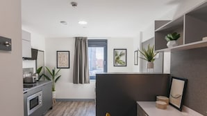 A modern kitchen with a built-in oven, a dining area with a table and chairs, and a view of the city through a window. - Student Only Onyx (Birmingham)