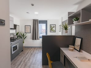 A modern kitchen with a built-in oven, a dining area with a table and chairs, and a view of the city through a window. - Student Only Onyx (Birmingham)