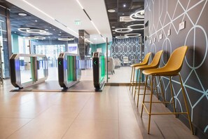 A modern lobby with a reception desk, a self-service kiosk, and a seating area with chairs. - Student Only Onyx (Birmingham)
