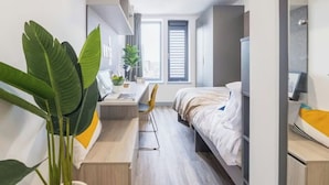 A modern hotel room with a bed, desk, chair, and large windows. - Student Only Onyx (Birmingham)