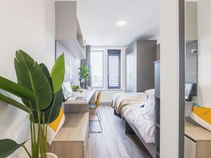 A modern hotel room with a bed, desk, chair, and large windows. - Student Only Onyx (Birmingham)