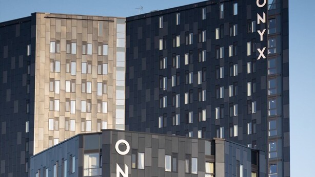 A modern high-rise building with a distinctive angular design, featuring the name 'ONYX' prominently displayed on its facade. - Student Only Onyx (Birmingham)