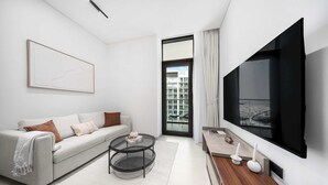 Ein modernes Wohnzimmer mit einer Couch, einem Couchtisch, einem Fernseher und einem großen Fenster.