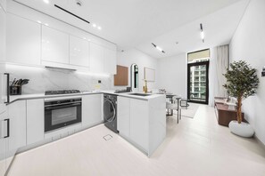 A modern kitchen with built-in appliances, a dining area, and a large window. - StayShort - Charming 1BR Retreat in JVC Sleeps 4 (JVC)