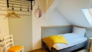 A bedroom with a bed, a chair, a hanging coat rack, and an air conditioning unit. - Villa Piazzetta (Bacău)