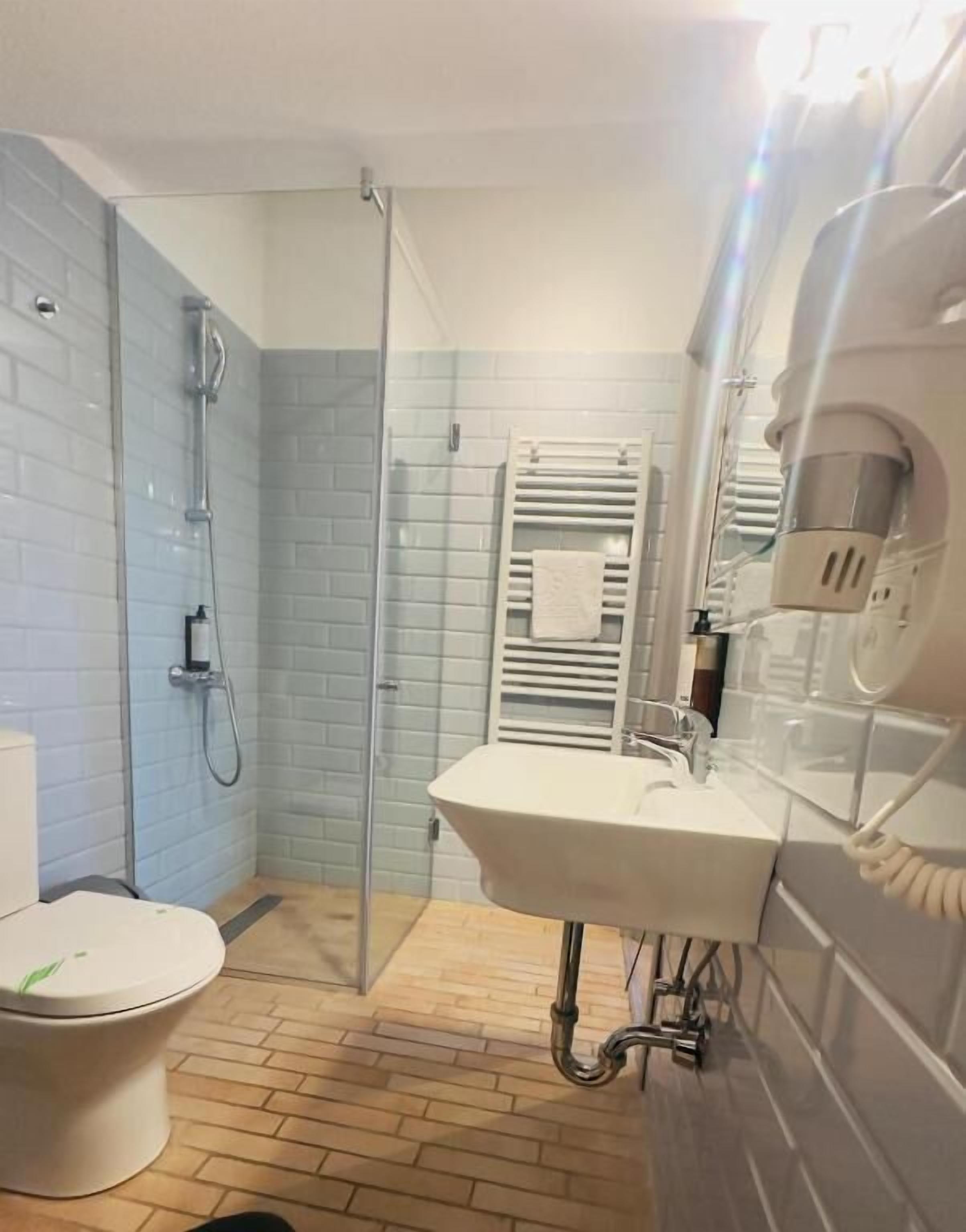 Un bagno con doccia, WC e lavandino.