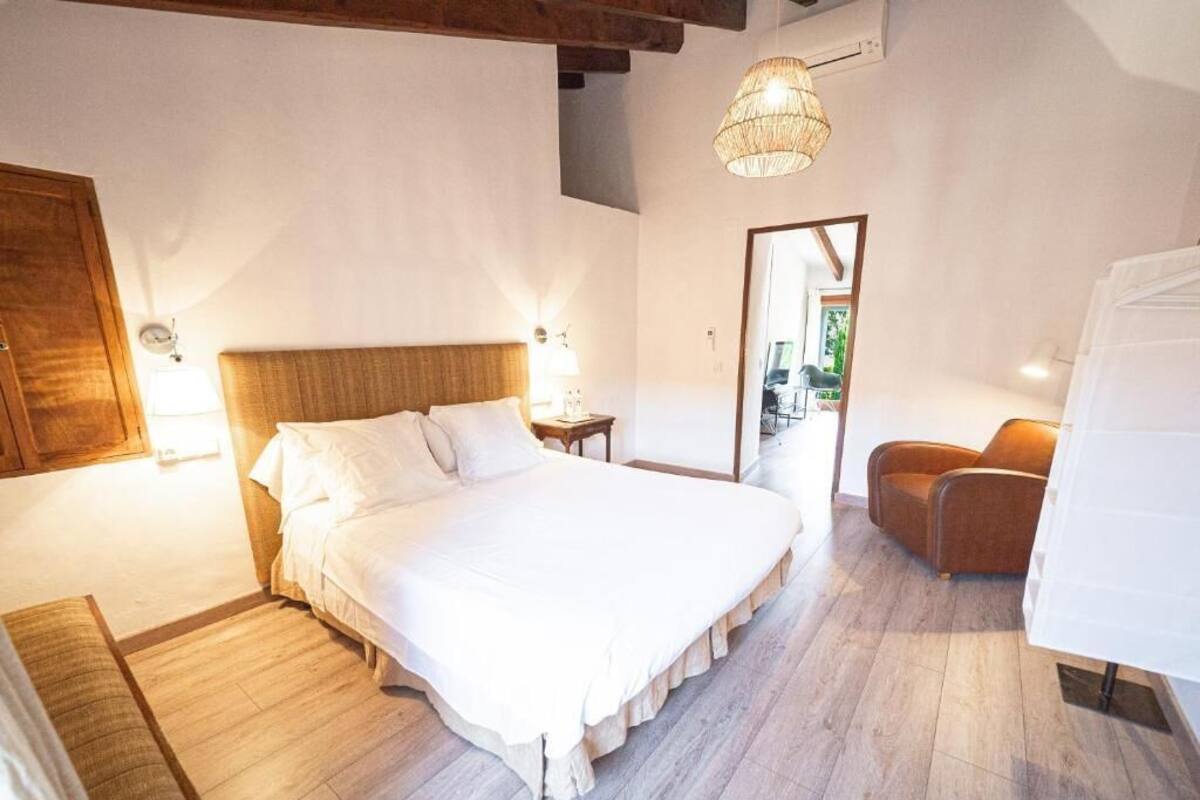 A bedroom with a large bed, bedside tables, a chair, a hanging light fixture, and a mirror.