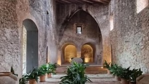 An interior with stone walls, wooden beams, and potted plants. - Finca Es Cabàs (Santa Maria del Camí)