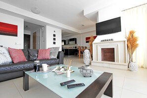 Un salon moderne avec un canapé, une table basse, une cheminée et un téléviseur fixé au mur.