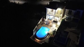 Une maison à deux étages avec une piscine, un espace salon extérieur et un balcon.