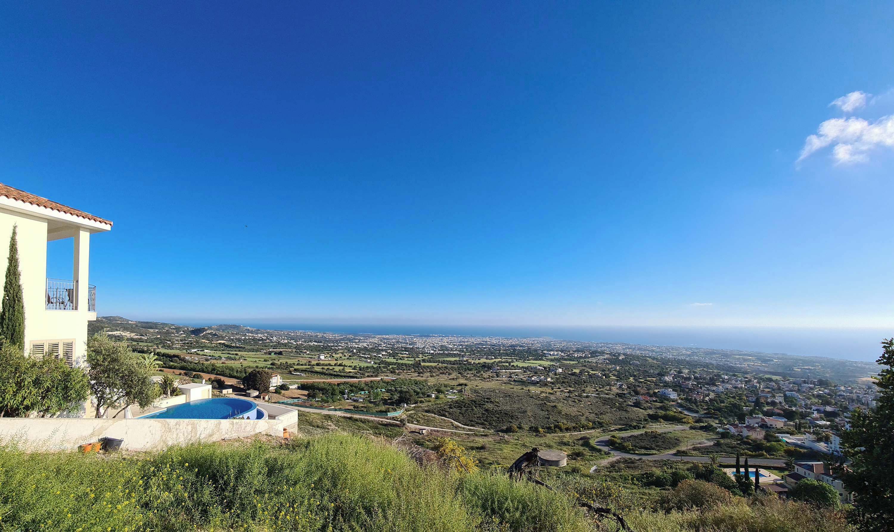 A residential property with a pool, a balcony, and a view of a coastal town.