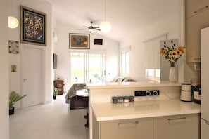 A modern kitchen with a central island, a ceiling fan, and a vase of sunflowers. - Special Launch Price! Amazing Sea View 1BR Villa, Garden (Polis Chrysochous)