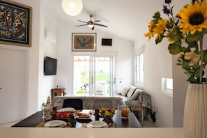 A dining area with a table set for two, a ceiling fan, and a view of the outdoors. - Special Launch Price! Amazing Sea View 1BR Villa, Garden (Polis Chrysochous)