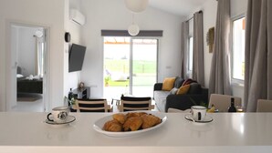 Un soggiorno moderno con zona pranzo, divano e televisione a parete.