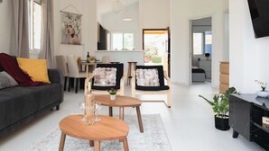 Un soggiorno moderno con un divano, due poltrone, un tavolino e una TV su un mobile.