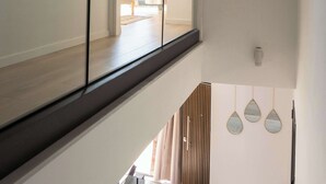 Ein modernes Interieur mit Glastrennwand, Holzboden und Blick auf eine Terrasse.
