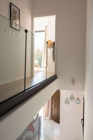 Ein modernes Interieur mit Glastrennwand, Holzboden und Blick auf eine Terrasse.