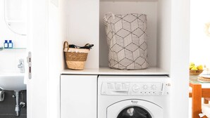 Un área de lavandería compacta con lavadora, una toalla estampada y una cesta.