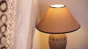 Luminária com cúpula de tecido e detalhes decorativos na base.