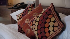 Cama com roupa branca e almofadas decorativas com padrões circulares.