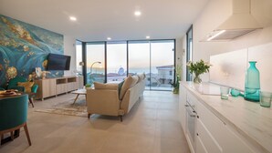 A modern living room with a sofa, TV, and a large window with a city view. - 200m NEW A Villa with private, heated pool and amazing ocean view (Costa Adeje)