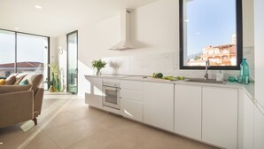 A modern kitchen with a large window, white cabinetry, a built-in oven, and a view of a building outside. - 200m NEW A Villa with private, heated pool and amazing ocean view (Costa Adeje)