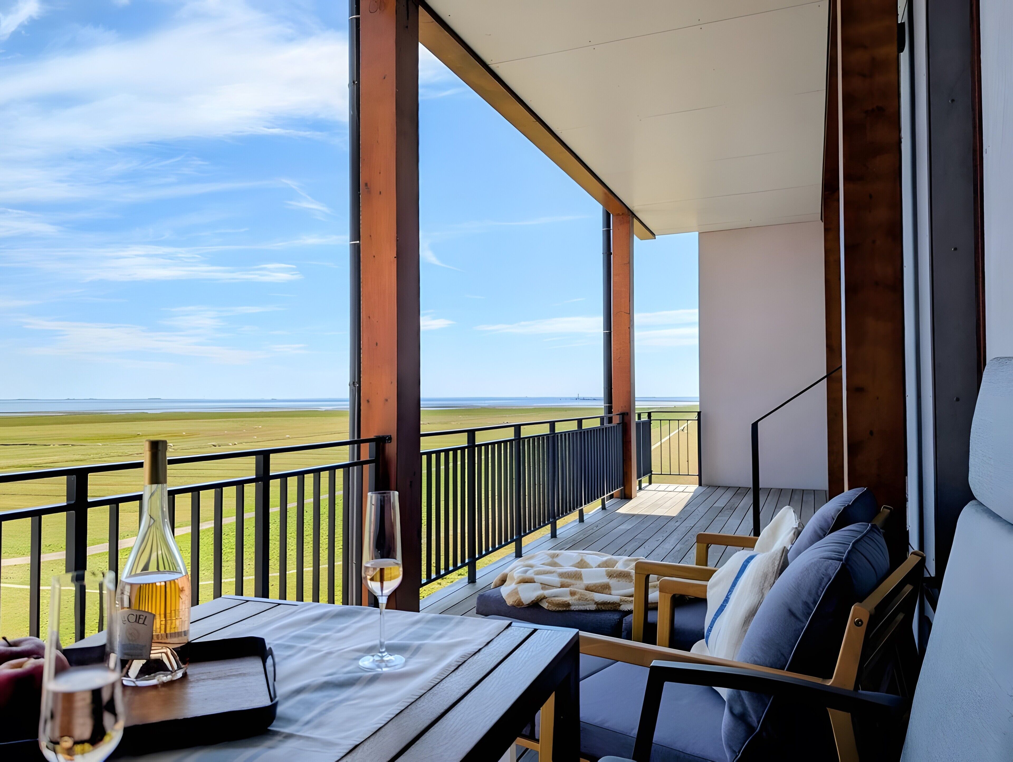A balcony with a table set for two, overlooking a grassy field.