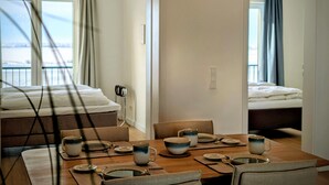 Ett hotellrum med en matplats, två sängar, havsutsikt och en balkong.