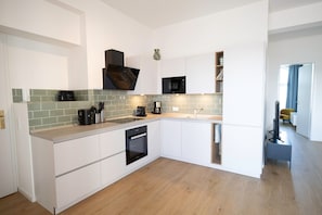 A modern kitchen with white cabinetry, a built-in oven, a coffee machine, and a microwave. - Apartment “Bodil” with Sea View, Balcony, and Wi-Fi (Pellworm)