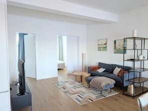 A modern living room with a sofa, a coffee table, and a bookshelf. - Apartment “Bodil” with Sea View, Balcony, and Wi-Fi (Pellworm)