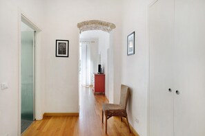 Ein Flur mit Holzboden, einem Sessel, einem roten Schrank und einem gerahmten Bild an der Wand.