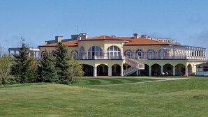 A large, two-story building with a red-tiled roof, multiple balconies, and a central staircase. - Ines - Golf and the Sea in Bulgaria (Balchik)