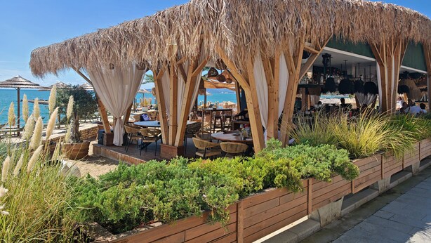 A beachside restaurant with outdoor seating, a thatched roof, and a view of the sea. - Ines - Golf and the Sea in Bulgaria (Balchik)