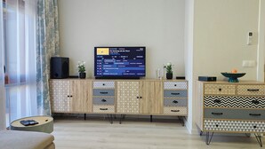 A living room with a TV, a cabinet with patterned drawers, a small table with a remote, and a sofa. - Ines - Golf and the Sea in Bulgaria (Balchik)