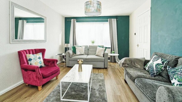Una sala de estar con un sillón rojo, sofá gris y una mesa de centro.