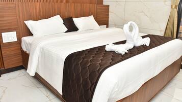 A neatly made bed with a brown quilt, white bedding, and two white towels arranged in a swan shape on the bed.